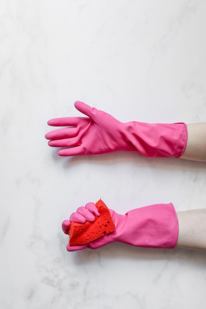 The Art of Drawing Readers In: Your attractive post title goes here Two hands wearing pink gloves holding a red sponge against a white marble background, showcasing cleaning or sanitation.